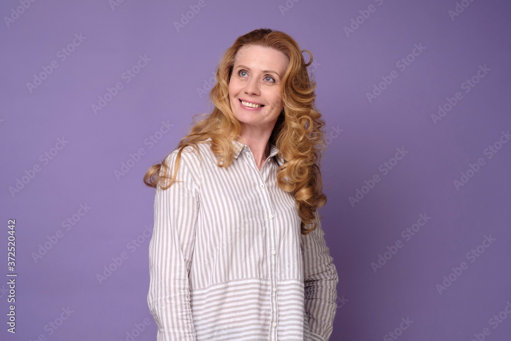 © Viktor Koldunov - Beautiful mature woman looking at camera and smiling while standing against colored background