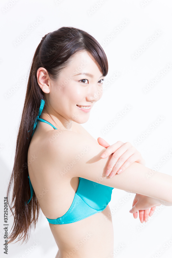 日焼け止めを塗る水着姿の女性