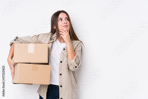 Foto Young caucasian woman moving to a new home looking sideways with doubtful and skeptical expression