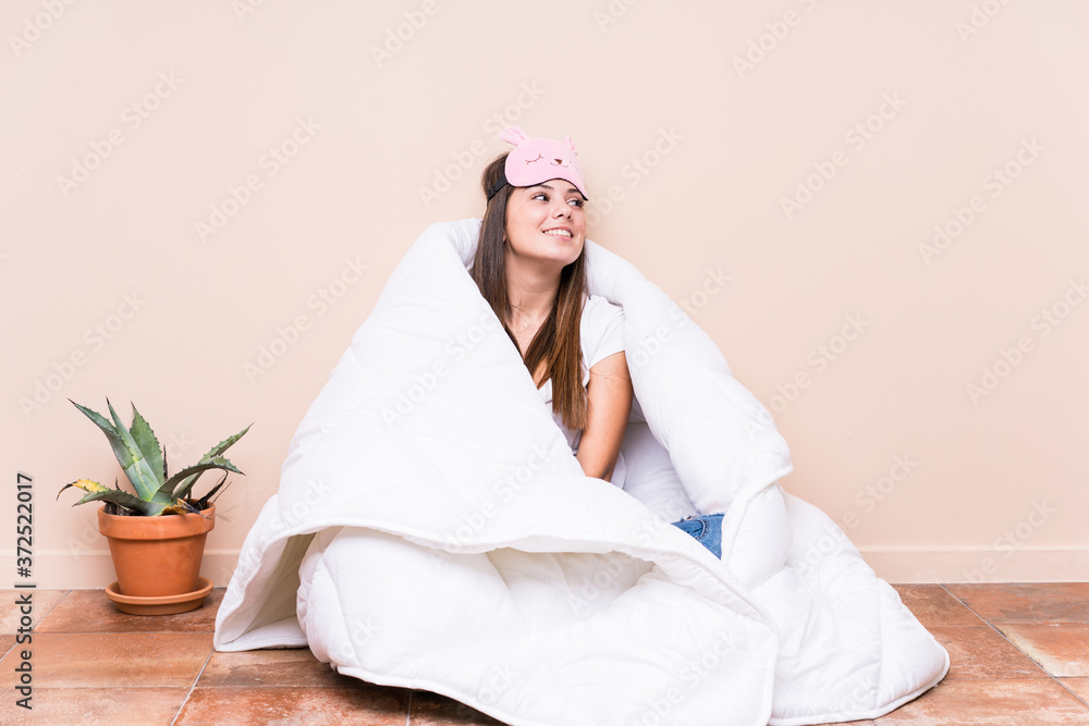 Young caucasian woman resting with a quilt looks aside smiling, cheerful and pleasant. Young caucasian woman resting with a quilt looks aside smiling, cheerful and pleasant.