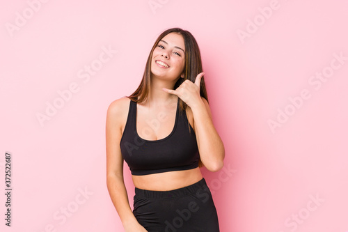 Young fitness caucasian woman isolated showing a mobile phone call gesture with fingers.
