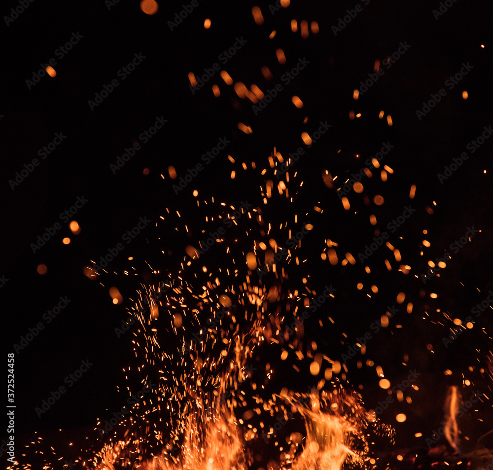 fire flames with sparks on a black background, close-up - obrazy, fototapety, plakaty 