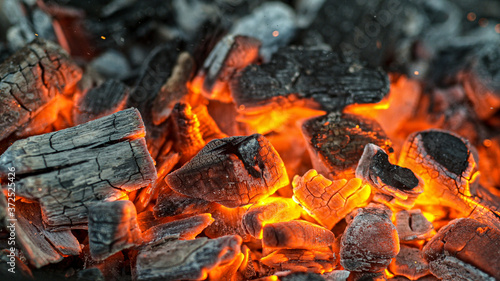 Фотография Barbecue Grill Pit With Glowing And Flaming Hot Charcoal Briquettes, Close-Up