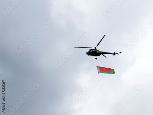 Helicopter flies in the sky with the Belarusian red-green flag. Political situation in Belarus