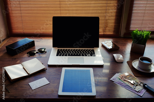 Mock up of business person luxury accessories and work tools, cup of american coffee, sunglasses, notepad, money bills, envelope, digital tablet and laptop computer, hipster office workplace desktop