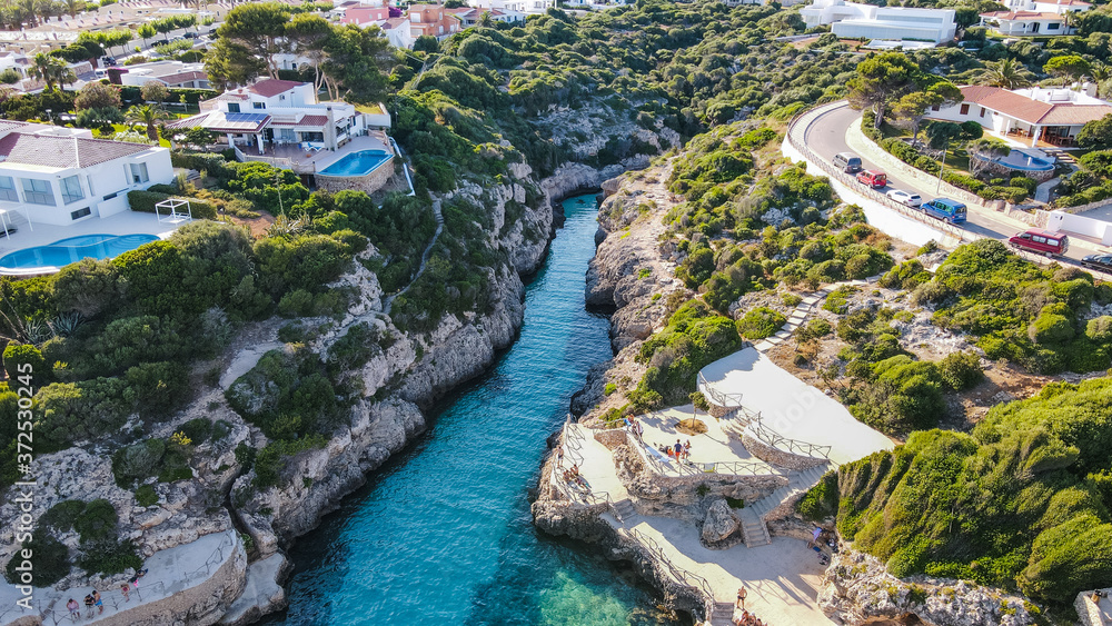 Beautiful aerial view of mediterranean bay with cliffs and holiday houses with swimming pools in Menorca, Spain Cala Brut, aerial top view drone photo