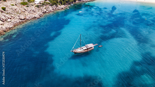 Aerial drone top down photo of pirates boat yacht with wooden deck anchored in open ocean sea © Ada