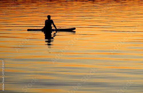 Wallpaper Mural Silhouetted paddle boarder at peace, watching the colorful setting sun from his board on the sea. Relaxed and 'at one with nature' concept. Torontodigital.ca