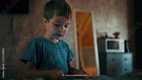 The boy plays on the phone and says something 