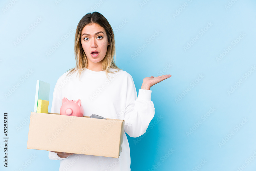 Young caucasian woman moving home isolated impressed holding copy space on palm. Young caucasian woman moving home isolated impressed holding copy space on palm.