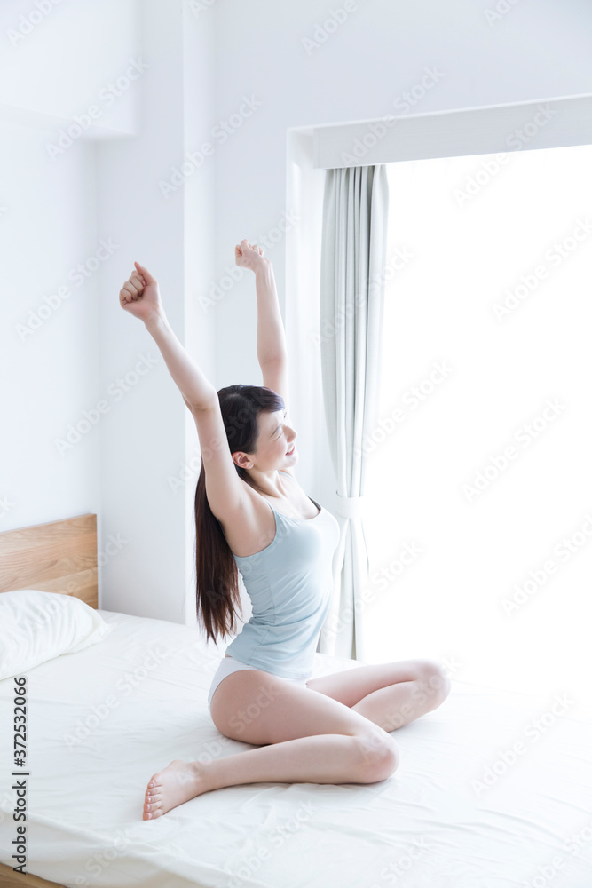 ベッドで伸びをする女性 ベッドで伸びをする女性