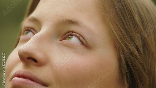 Close up shot of smiling caucasian woman with green azzure eyes looking up. High quality photo