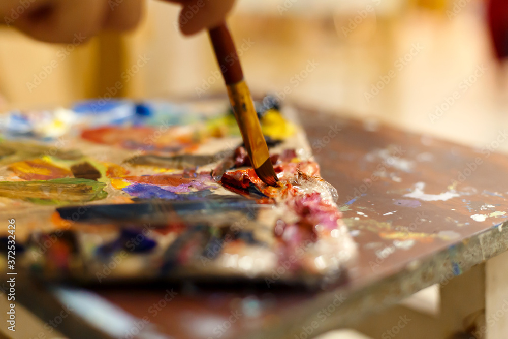 Obraz premium Close-up of an easel with paints, the artist paints a brush. Painting a picture.
