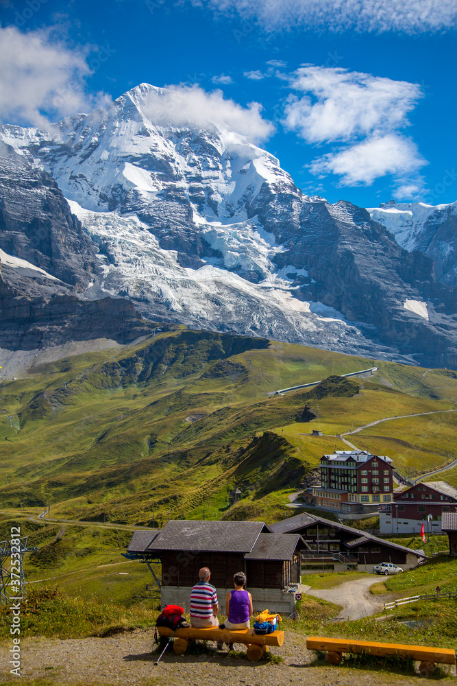 Hikers resting above the village of Kleine Scheidegg and The Eiger, a mountain of the Bernese Alps, overlooking Grindelwald and Lauterbrunnen in the Bernese Oberland of Switzerland