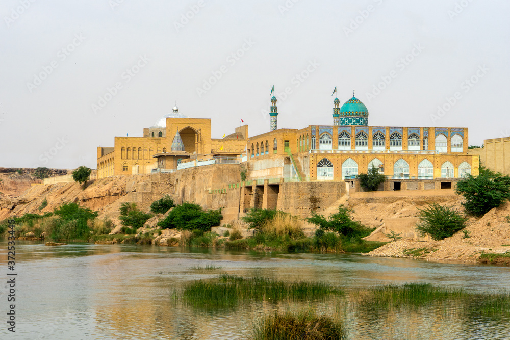 In Iran, the city of Shushtar is a green oasis surrounded  by desert. A mosque is situated along the river. 
