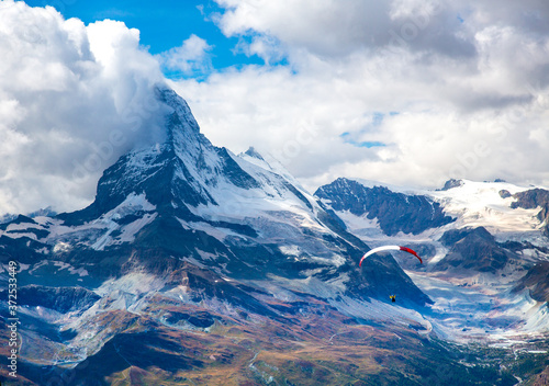 A para glider sails in front of the Matterhorn. It is a mountain of the Alps, straddling Switzerland and Italy, its summit is 4,478 metres (14,692 ft) high.