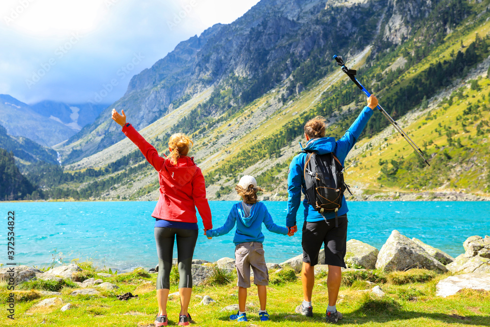 family trekking- father, mother and child happy in front of beautiful mountain lake