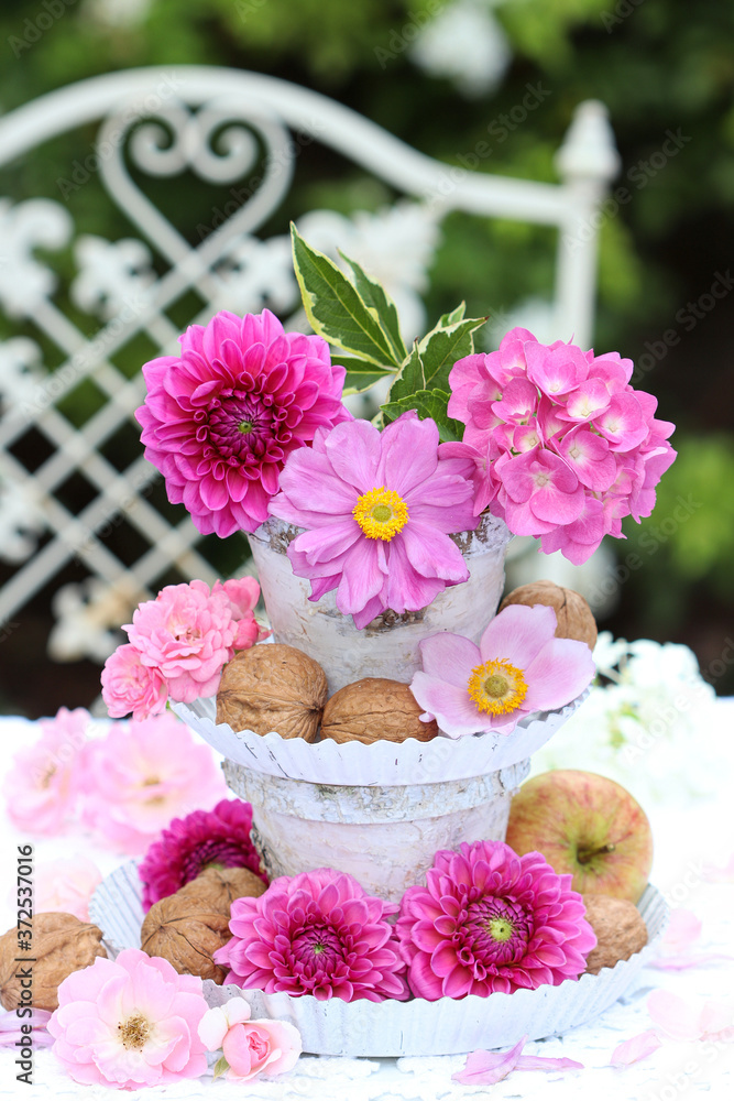 Eragere mit pink Blumen, Walnüssen und Apfel als romantische Gartendekoration