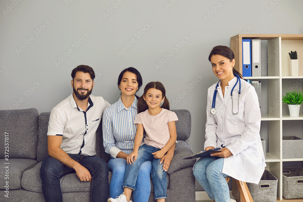 Portrait of a doctor and a happy family are looking at the camera in the clinic office. Portrait of a doctor and a happy family are looking at the camera in the clinic office.