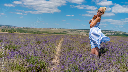 Fototapeta Naklejka Na Ścianę i Meble -  Joyful lady on a lavender field with charismatic appearance sunglasses stands smiling stands