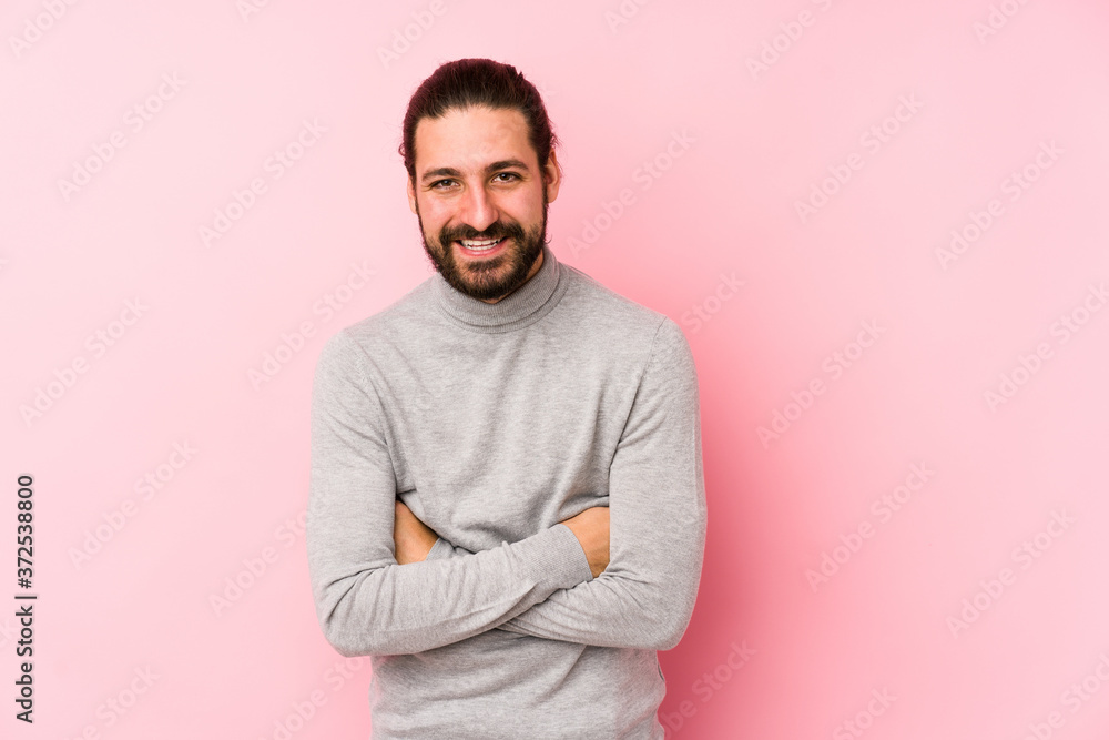 Young long hair man isolated on a pink background laughing and having fun. Young long hair man isolated on a pink background laughing and having fun.