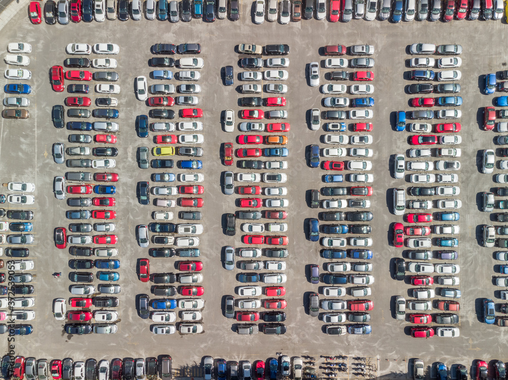 Vista aérea cenital sobre un estacionamiento público con carros de diferentes colores estacionados.