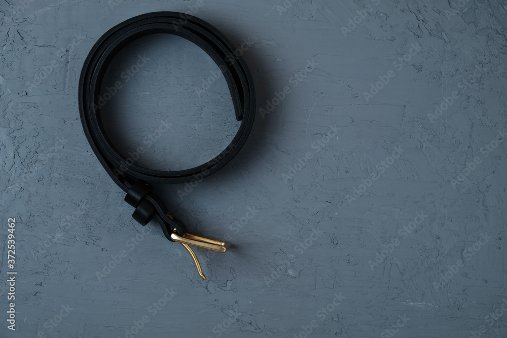 Handmade genuine leather belt on dark concrete background Handmade genuine leather belt on dark concrete background