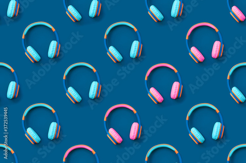 Seamless pattern of blue and pink colored headphones on blue background. Minimalistic fashion music concept. Trendy color of the year concept. Top view, flat lay
