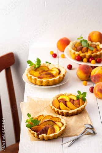 Open pie from shortcrust pastry with peaches, peach clafoutis on white table