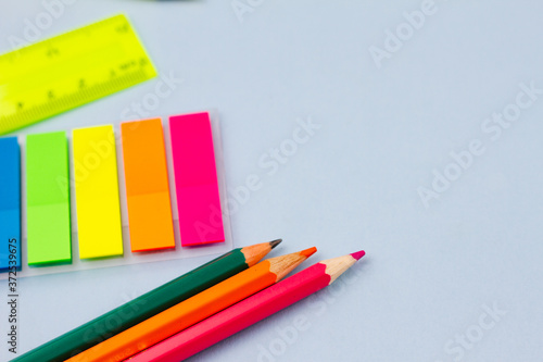 Colored stickers and pencils on a blue background. View from above. Place for your text. Education concept.