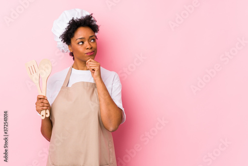 Young african american cook woman looking sideways with doubtful and skeptical expression.