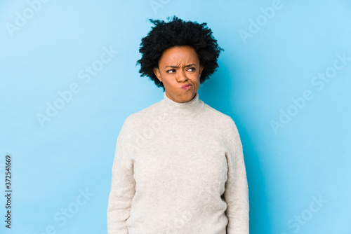 Middle aged african american woman against a blue background isolated confused, feels doubtful and unsure.