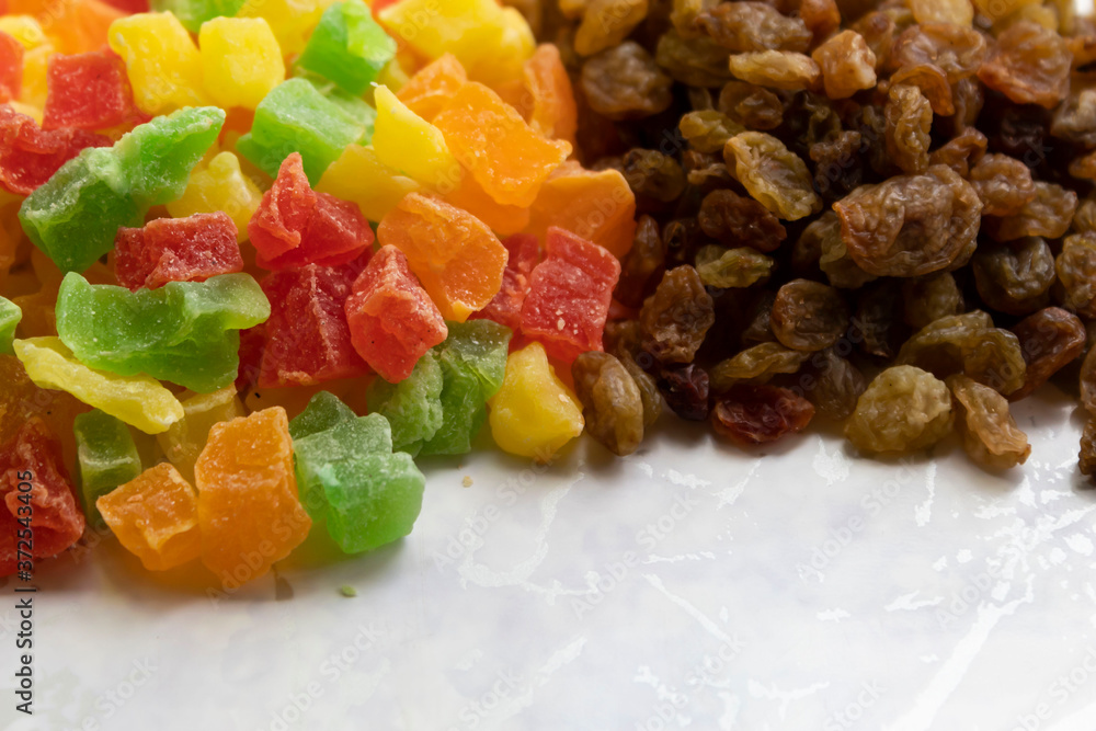 On a white background lies a slide of multi-colored pieces of candied fruit and raisins.. On a white background lies a slide of multi-colored pieces of candied fruit and raisins..