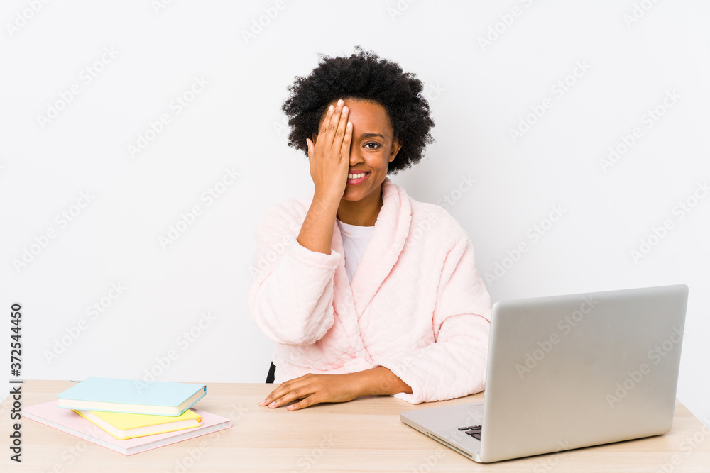 Middle aged african american woman working at home isolated having fun covering half of face with palm. Middle aged african american woman working at home isolated having fun covering half of face with palm.