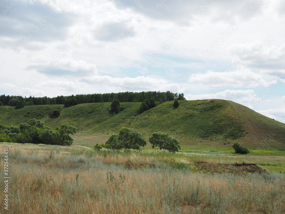 Beautiful rural summer nature landscape.Sunny view of large meadow and green woods.Amazing blue sky with fluffy clouds over land.Bright color nature sunrise scene with beautiful green hills.