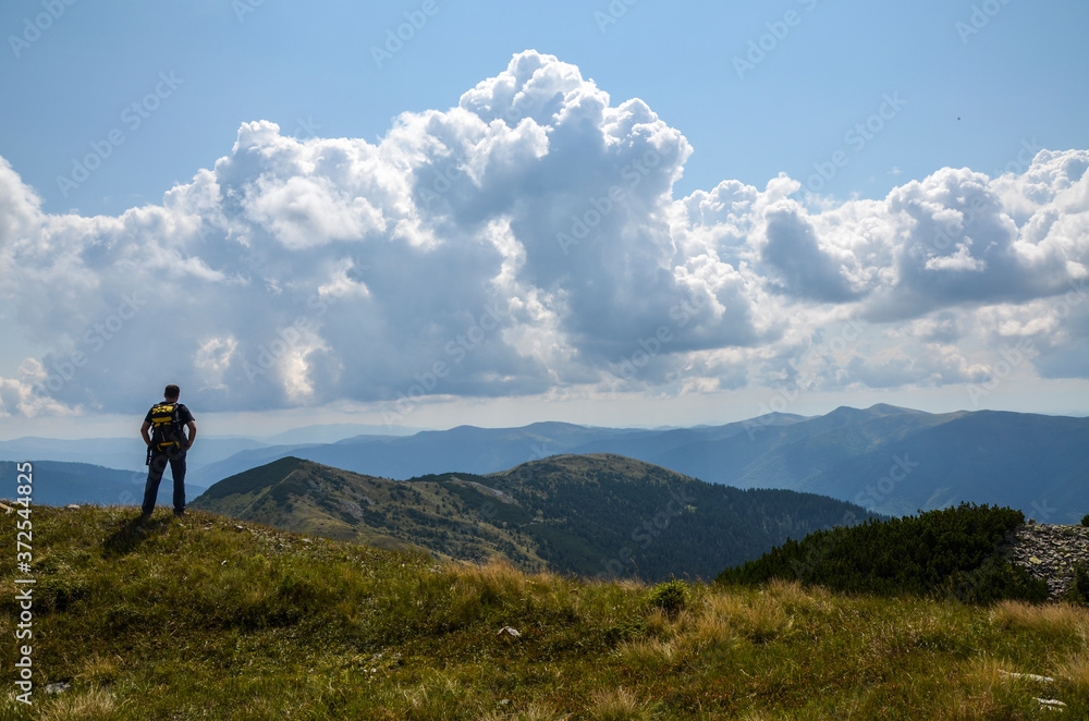 Hiker with backpack standing on top of a mountain and enjoying landscape. Carpathians, Ukraine