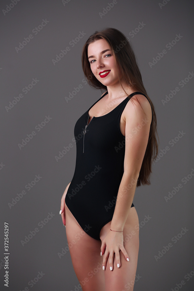 Fototapeta premium Attractive long haired beautiful woman with perfect body posing in swimsuit, smiling.