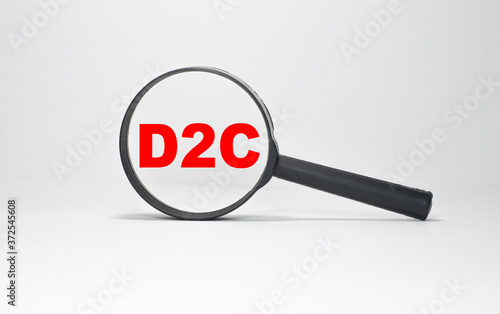 D2C inscription in a magnifying glass on a boundless white background
