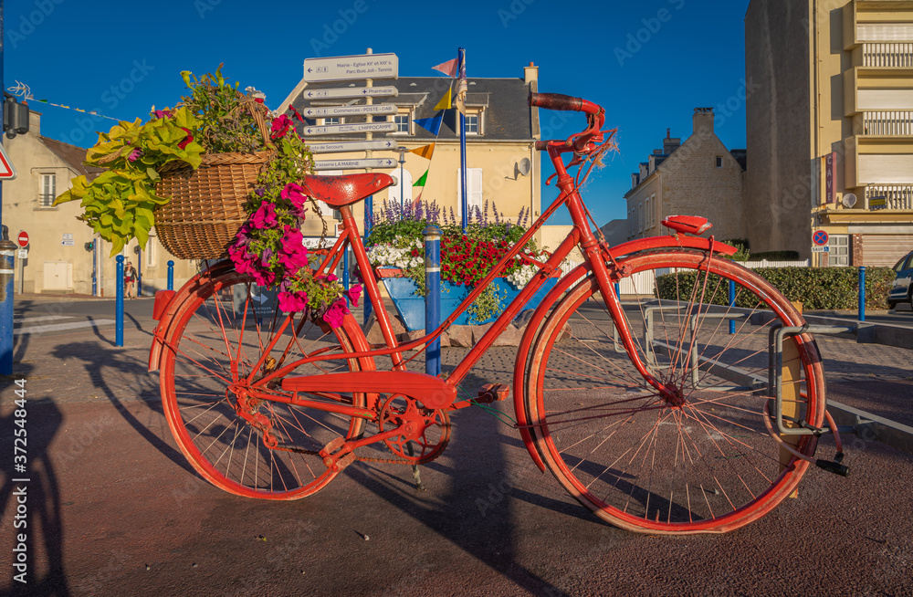Langrune Sur Mer, France - 08 04 2020: The red bicycle with its basket of flowers at sunrise