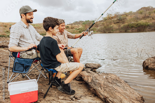 Male members of three generation family fishing together