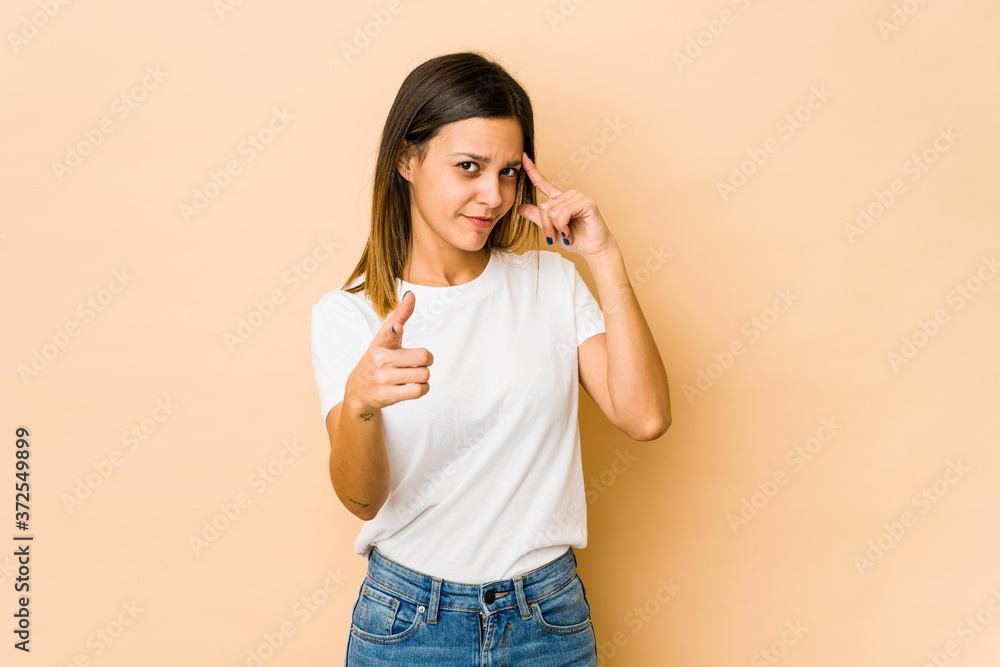 Young woman isolated on beige background pointing temple with finger, thinking, focused on a task. Young woman isolated on beige background pointing temple with finger, thinking, focused on a task.
