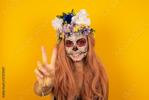 Young caucasian woman standing against gray wall showing and pointing up with fingers number two while smiling confident and happy.