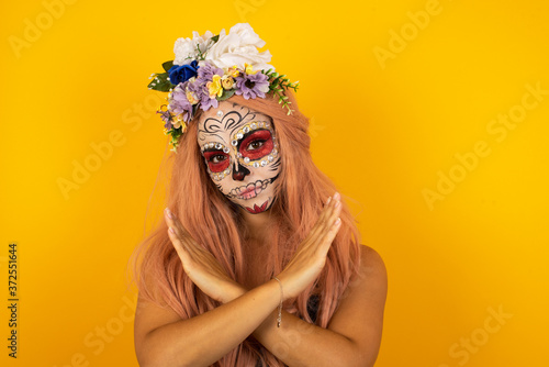 Young beautiful brunette girl wearing halloween make up standing over isolated background. Has rejection angry expression crossing hands doing refusal negative sign.