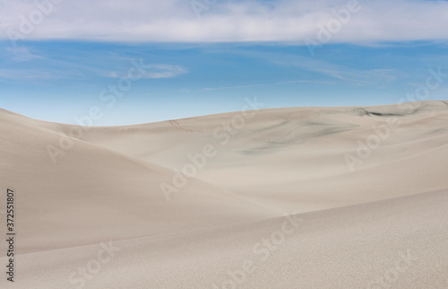Sand dunes against blue sky.