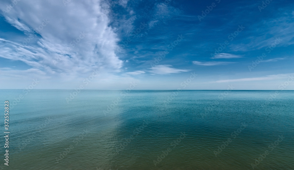 The surface of the calm sea under a cloudy blue sky.