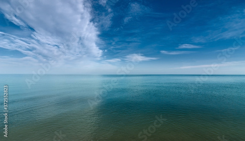 The surface of the calm sea under a cloudy blue sky.