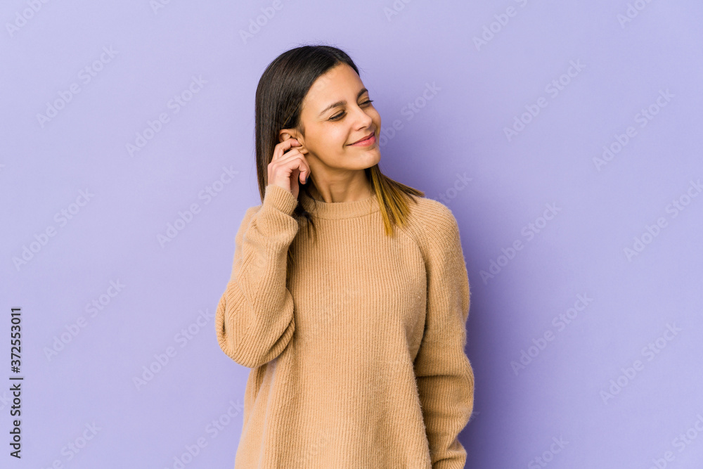 Young woman isolated on purple background covering ears with fingers, stressed and desperate by a loudly ambient. Young woman isolated on purple background covering ears with fingers, stressed and desperate by a loudly ambient.