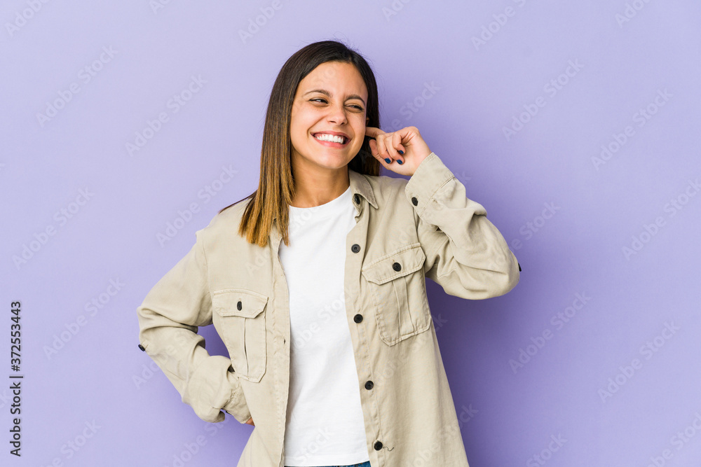 Young woman isolated on purple background covering ears with hands. Young woman isolated on purple background covering ears with hands.