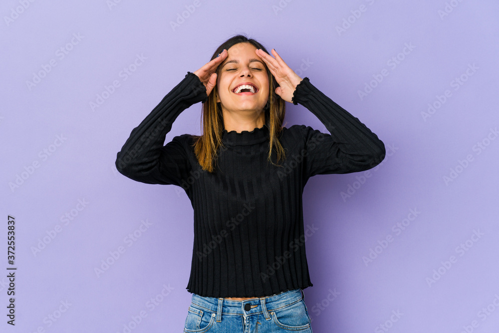 Young woman isolated on purple background laughs joyfully keeping hands on head. Happiness concept. Young woman isolated on purple background laughs joyfully keeping hands on head. Happiness concept.