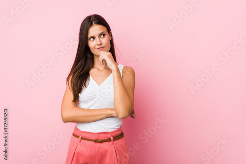 Young cute woman looking sideways with doubtful and skeptical expression.